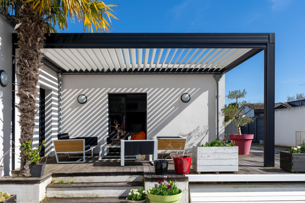 A black pergola over a patio with a clear roof