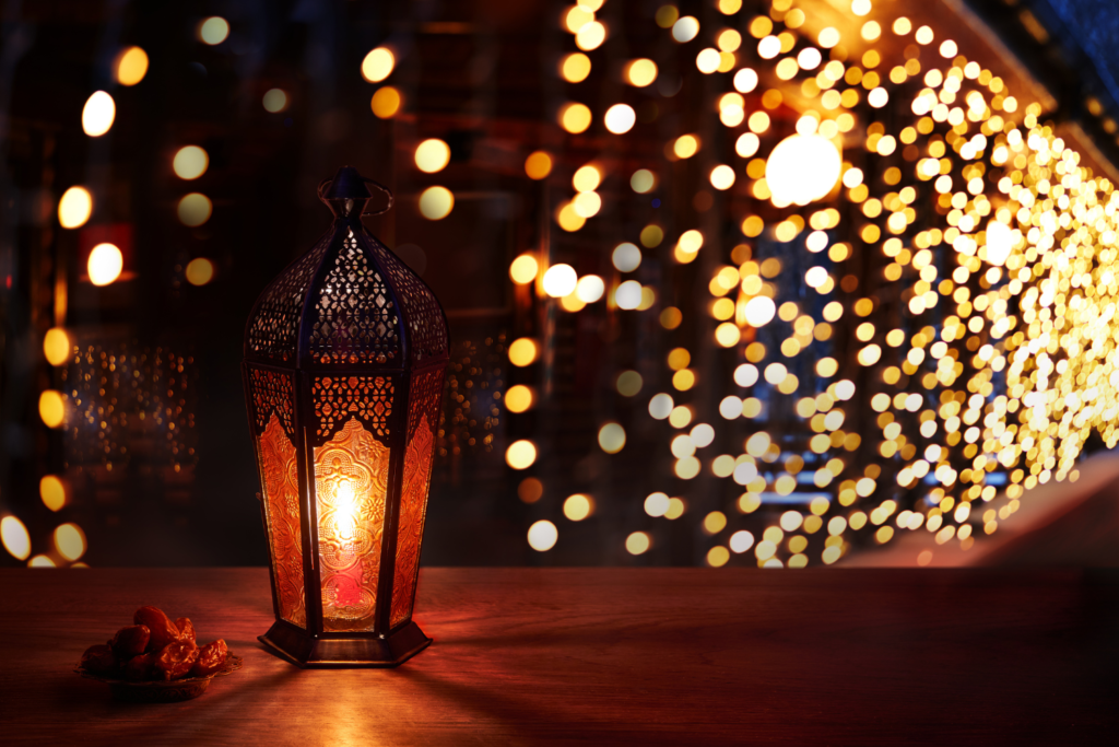 a lighted lantern sitting on a railing with string lighting in the background