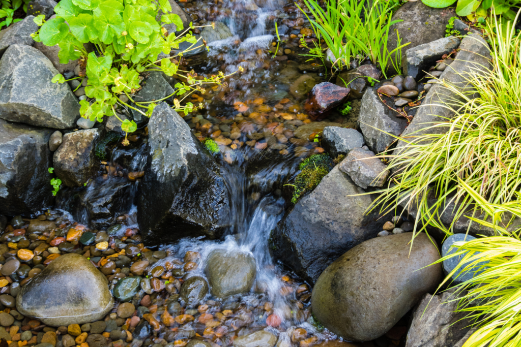 A backyard water feature with water fall and rocky running water.