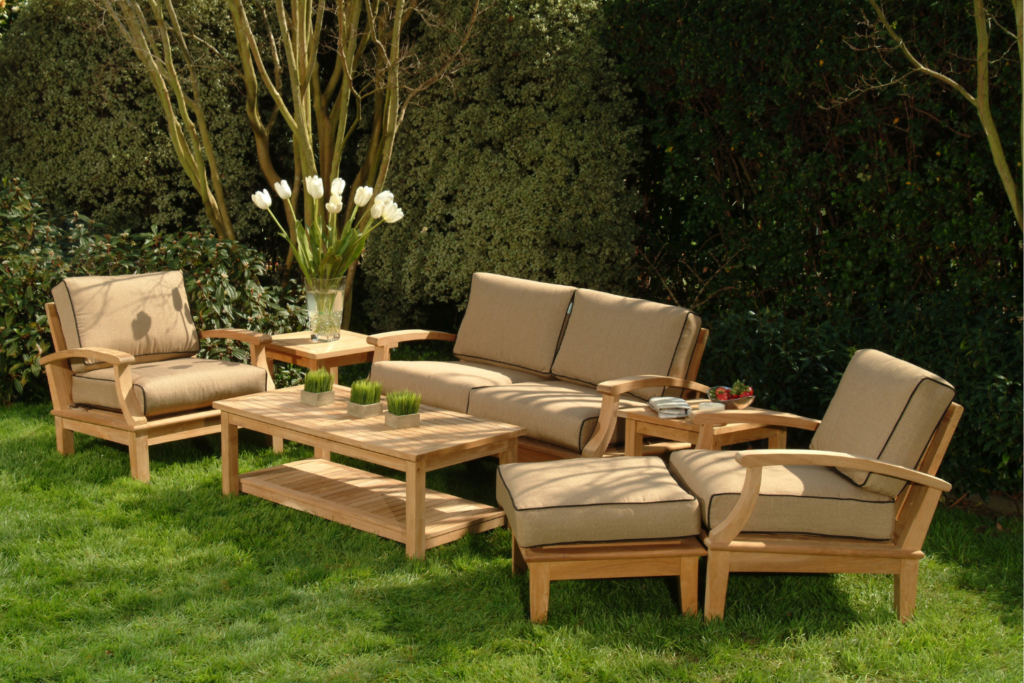 A backyard wooden patio furniture set with tan cushion pillows and a privacy fence in the background.