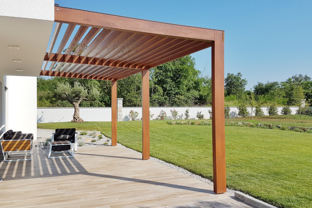 a pergola over a cement patio with backyard in background.