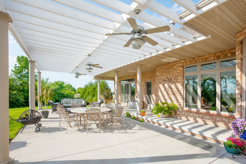 a pergola over a concrete patio with patio furniture dining set and firepit.