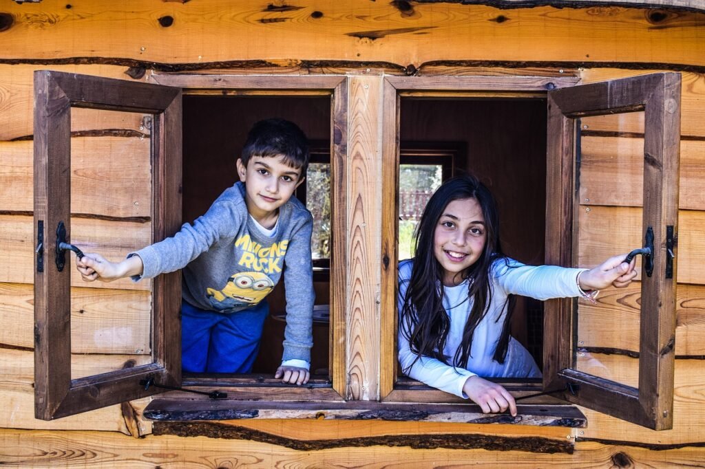 two children looking out windows of a fort