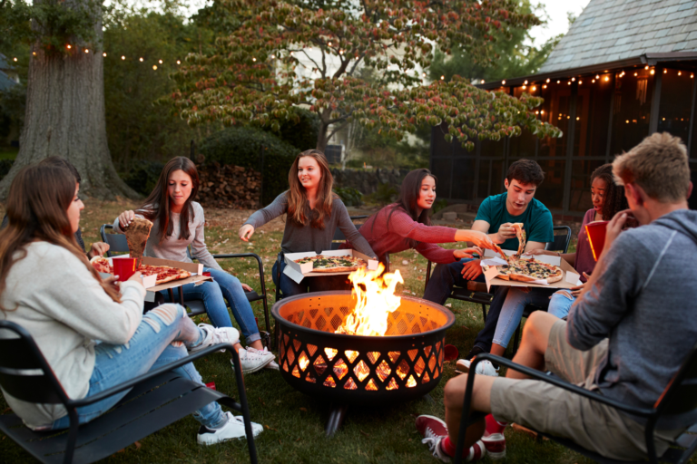 group of people gathered around a backyard fire pit