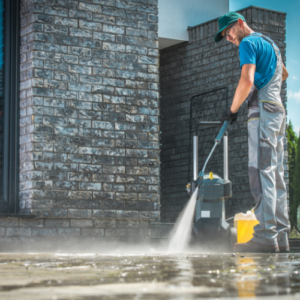 man pressure washing a patio